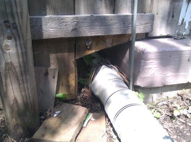 Downspout opening in fence